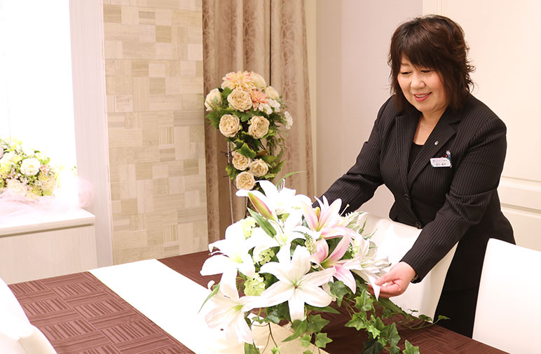 葬儀式場でお葬式スタッフが斎場の生花を整えている様子