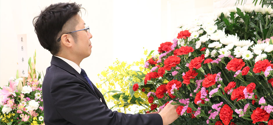 家族葬のともか葬儀スタッフが葬式祭壇の生花を整えている様子