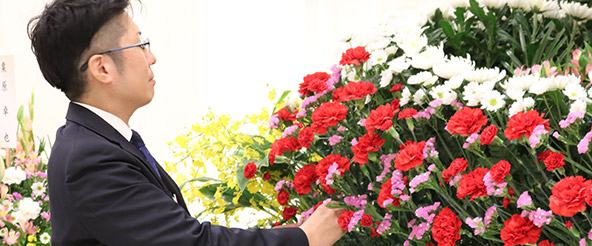 葬式会場の生花を整えている葬儀スタッフ